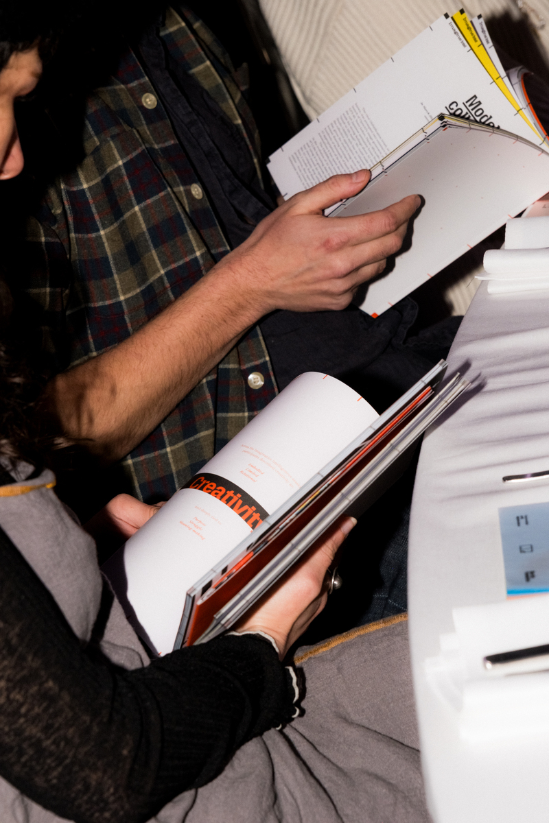 People holding the magazine Imagine Intel: Creative Purpose at the Dawn of AI at a dinner in Berlin